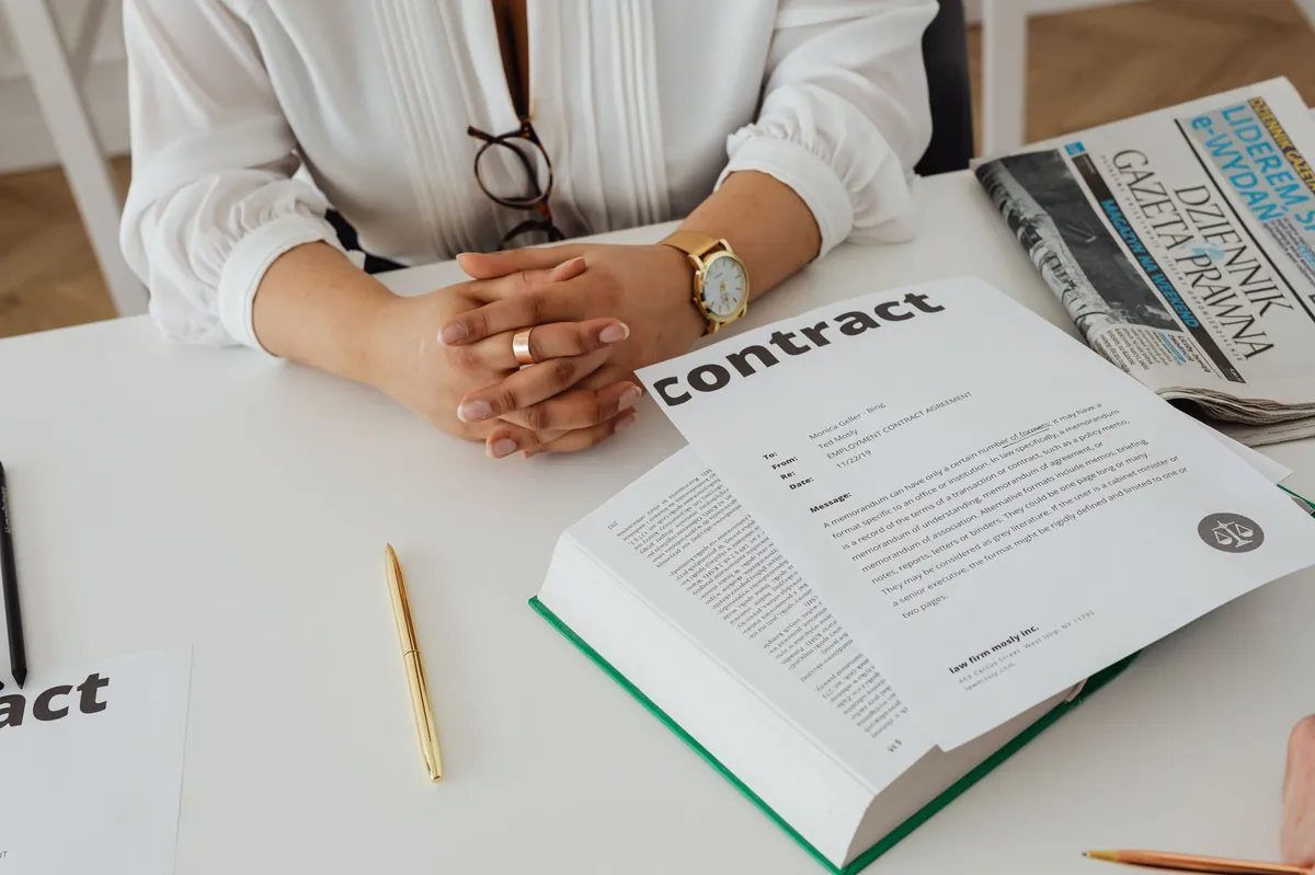 Businesswoman at a desk reviewing a contract alongside legal documents and a newspaper.